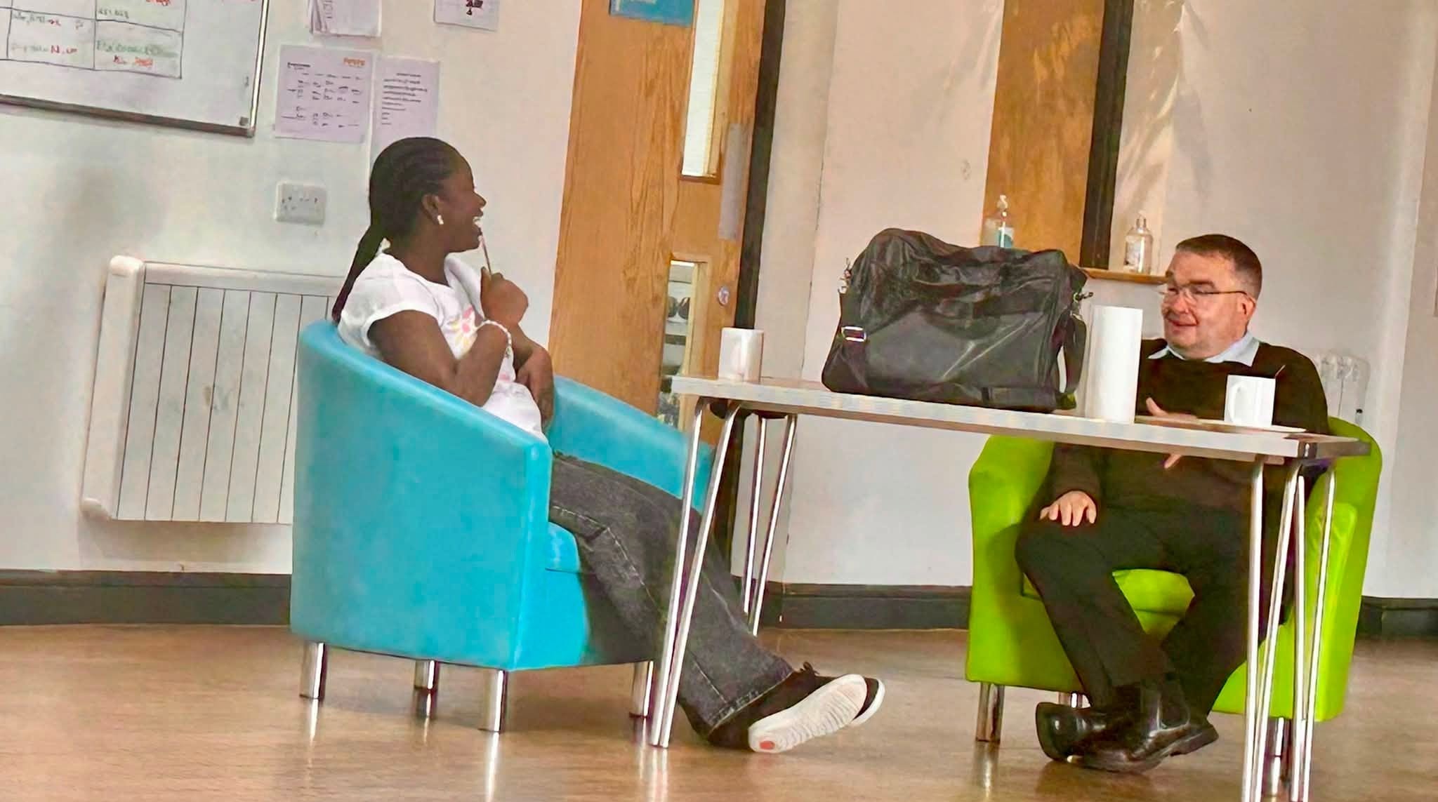 Photo of two people in conversation smiling 