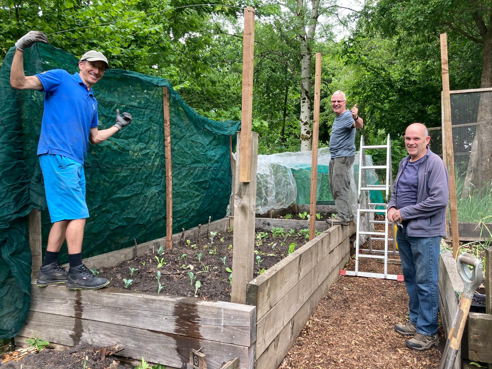 group of men smiling into the camera by raised bedding