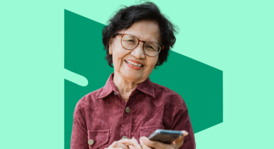 An older woman using a mobile and smiling at the camers