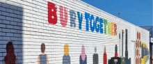 A picture of a painted brick wall with people and the phrase Bury Together