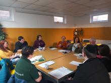 Picture of the group committee meeting with people gathered around the table talking