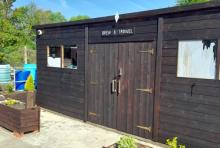 A photo of a brown shed at the allotments on a sunny day