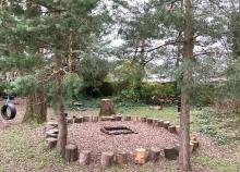 Photograph of Woodland trees with wooden seating sculptures in a circle