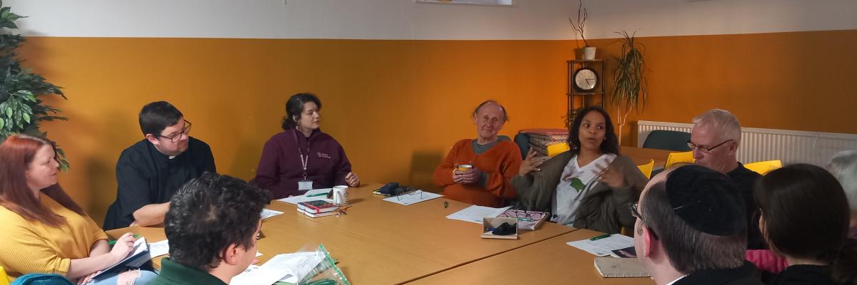 Picture of the group committee meeting with people gathered around the table talking