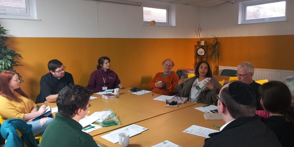 Picture of the group committee meeting with people gathered around the table talking