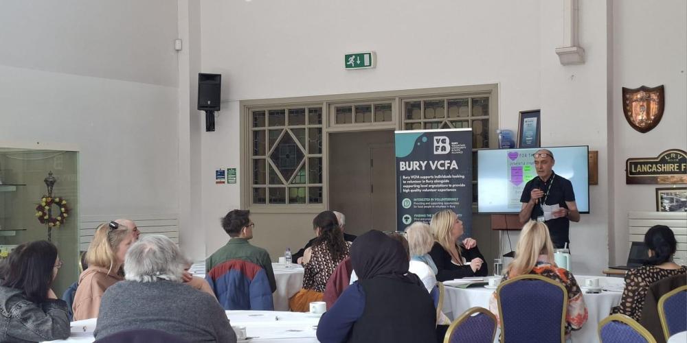 Picture of a group of people watching a presentation board and speaker