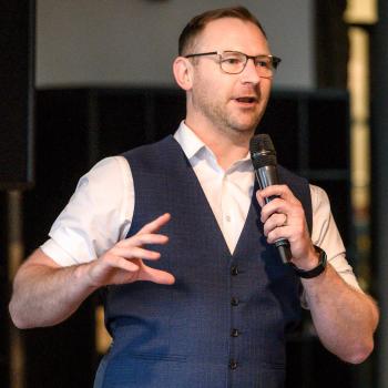 Photograph of a male delivering a speech to an audience